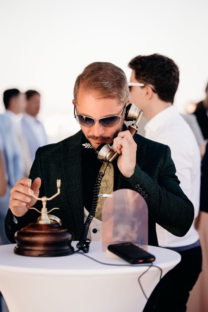 A guest in a green suit leaving a message on a wooden vintage telephone