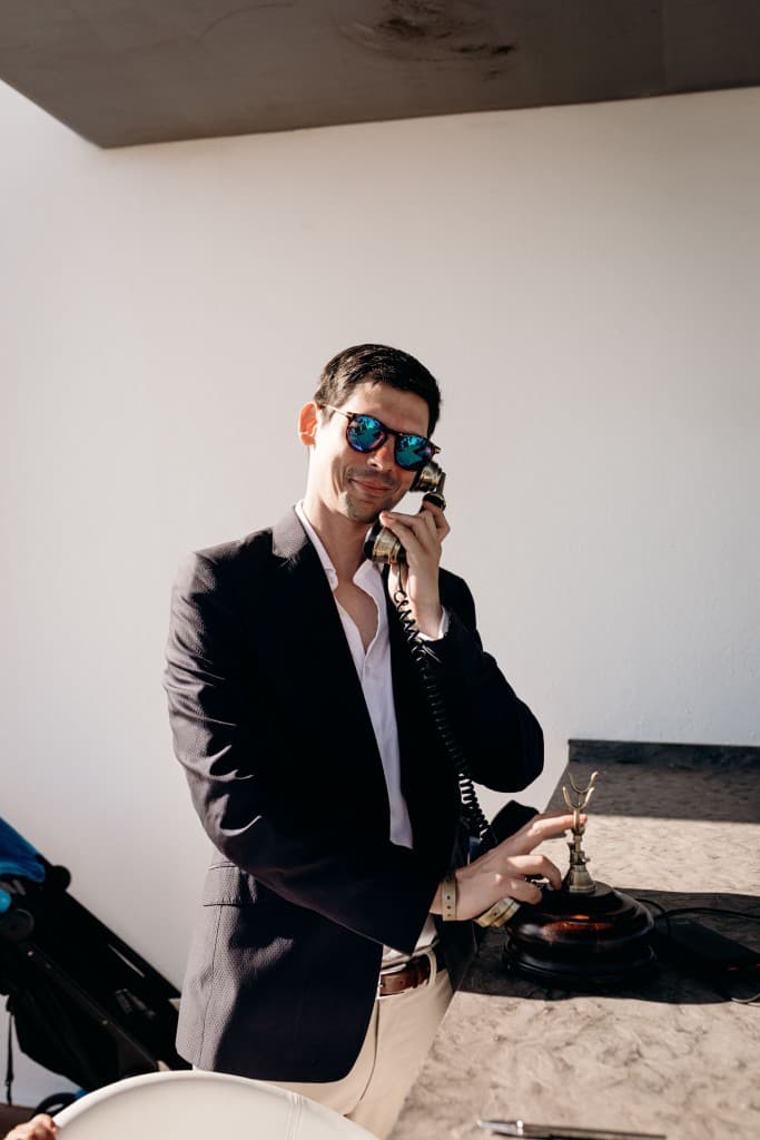 A guest in a navy blazer using a wooden candlestick telephone