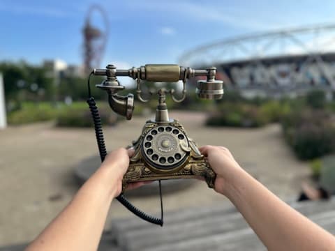 Hands holding an ornate brass candlestick telephone