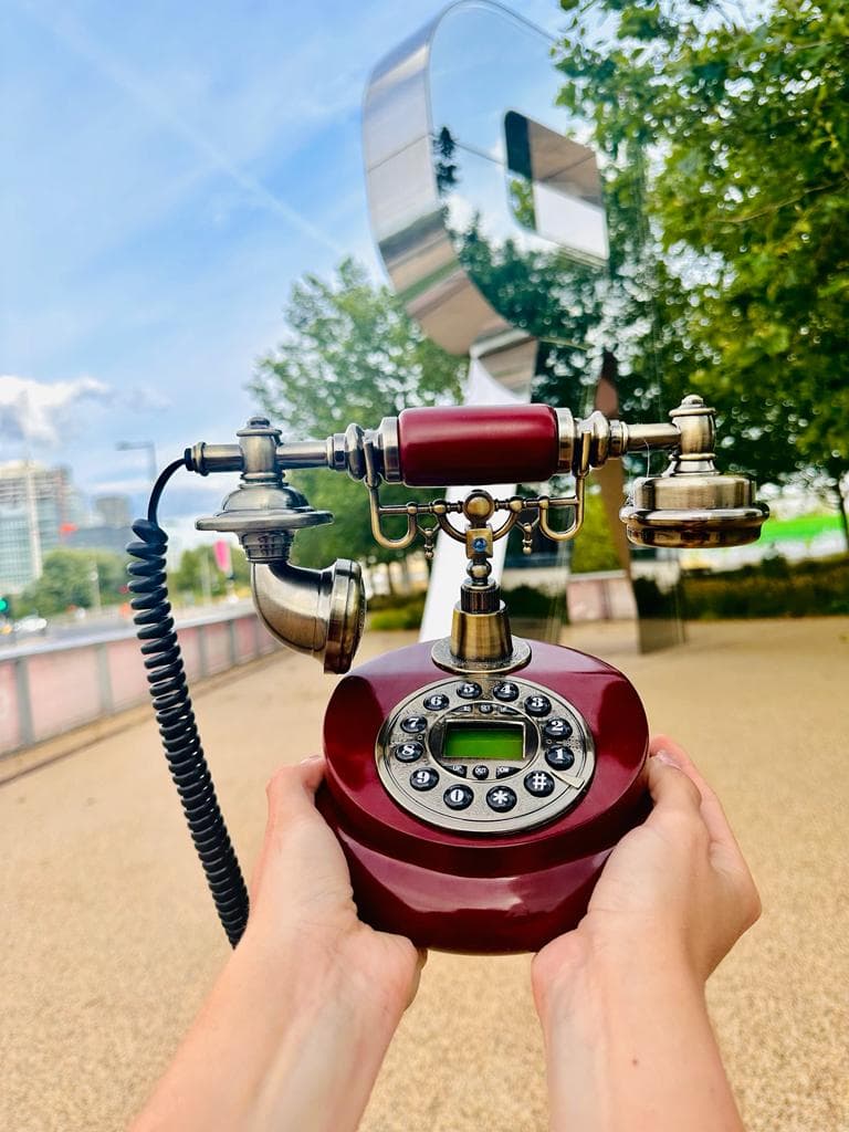 Hands holding a burgundy vintage telephone