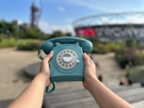 Hands holding a teal rotary telephone