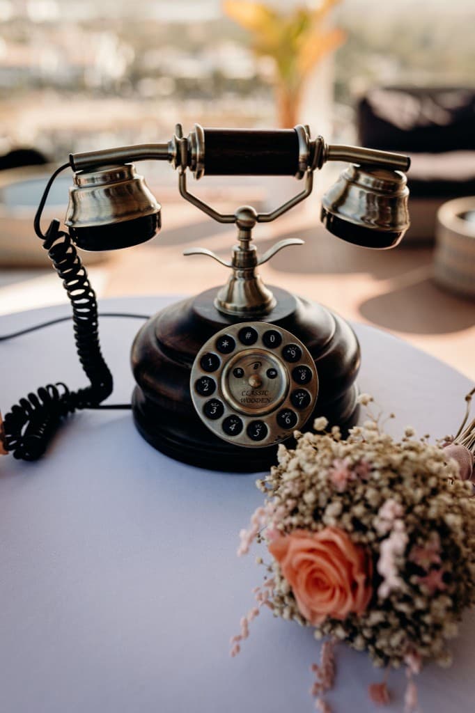 A wooden vintage telephone beside a bouquet of dried roses